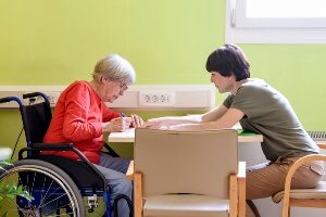 a caregiver is coercing a woman in a wheelchair to sign a document