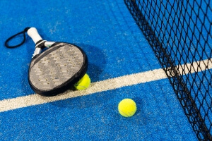 image shows closeup of two pickleball paddles lying on blue court floor