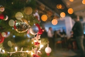 image of a holiday tree with a party going on in the background