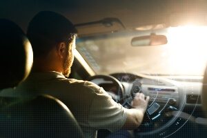 back of a young male driver looking through the windshield of a car